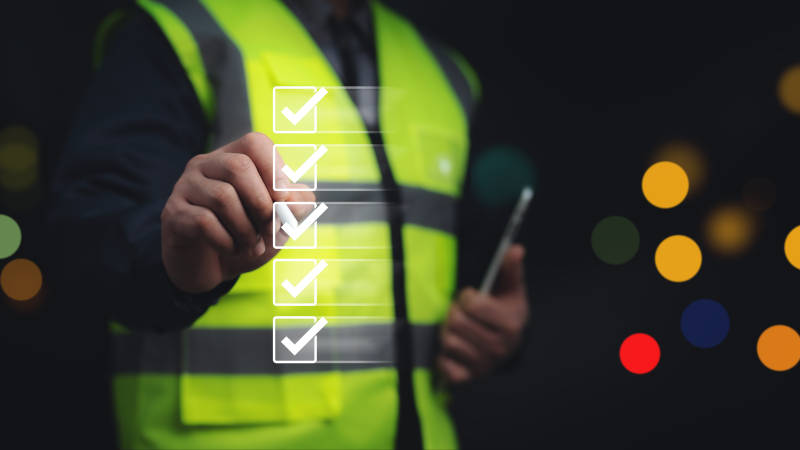 person in safety vest checking off list of safety checks